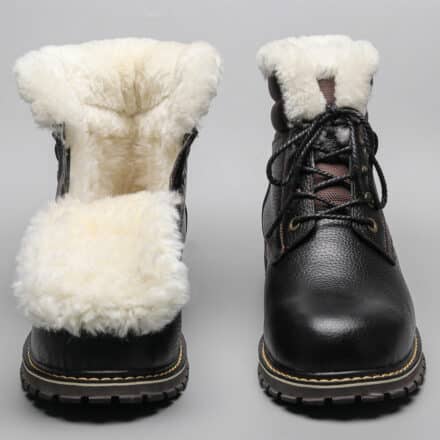 Bottes chaudes classiques en cuir noir et fourrure blanche. La boite de gauche est ouverte pour montrer la fourrure blanche.
