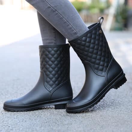 Bottes de pluie noires pour femme à imprimés carreaux en caoutchouc sur sol en béton, jean gris