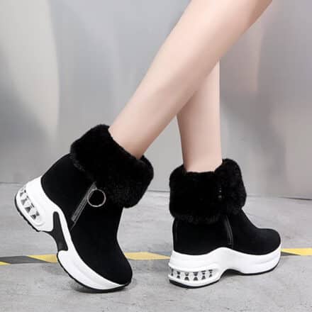 Bottines de ski noires à plateforme épaisse blanche pour femme. Fourrées, elles sont un zip sur le côté avec un anneau.