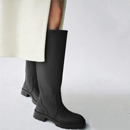 Botte noires hautes porté par une femme avec un long manteau beige claire