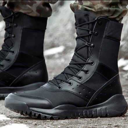 Bottes noir a lactes portées par un hommes en pantalon militaire sur un sol en goudron