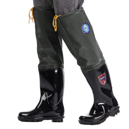 Bottes noires portées avec des cuissardes vertes au cordon jaune au niveau des genoux.