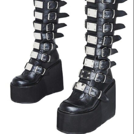 Bottes noires avec fermetures en sangle en métal, fond blanc.