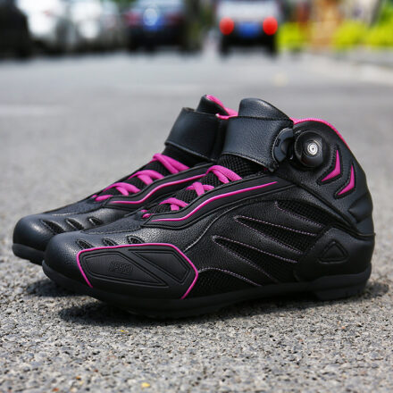 Bottes de moto noire et rose posées sur une route avec une voiture en arrière plan.