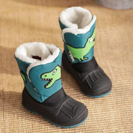 Botte bleu, noire et blanche avec un motif dinosaure sur le dessus sont posées sur un sol beige