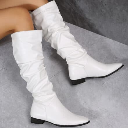 Bottes blanches pour femmes plissées, portée sur un tissu gris
