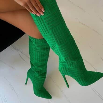 des bottes vertes hautes avec une main dessus sur un sol blanc