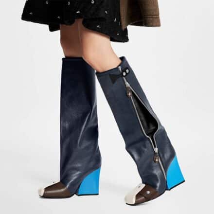 Bottes compensées bleues et marron avec fermeture éclair sur fond blanc portées avec une jupe marron