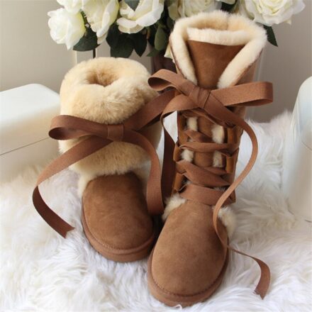 Très jolies bottes en cuir de mouton et laine de mouton véritable. Très chaudes, confortables et robustes elles sont aussi très féminines avec leurs larges lacets esprit ruban. Elles sont posées près de fleurs.