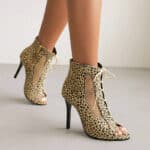 Sandales bottes à motif léopard à talons hauts fins pour femmes portées par une femme dont on ne voit que les pieds