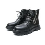 Paire de bottes noires à lacets, avec deux lanières avec boucle argentée par-dessus les lacets, et une fermeture éclair argenté sur le côté extérieure de la chaussure qui passe sous les boucles argentées. De trois-quart sur fond blanc.