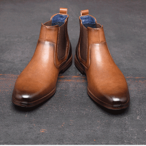 Paire de bottines homme classique couleur camel de face, avec le bout plus foncé presque noir. Sur un sol gris.
